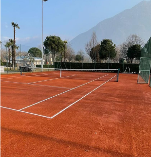 Campo da tennis outdoor in terra rossa RedPlus con sfondo montano e giornata soleggiata
