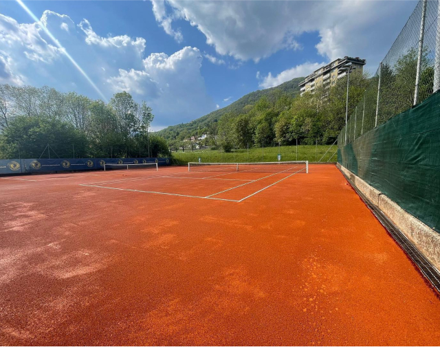 Campo da tennis outdoor in terra rossa RedPlus con sfondo naturale e giornata soleggiata