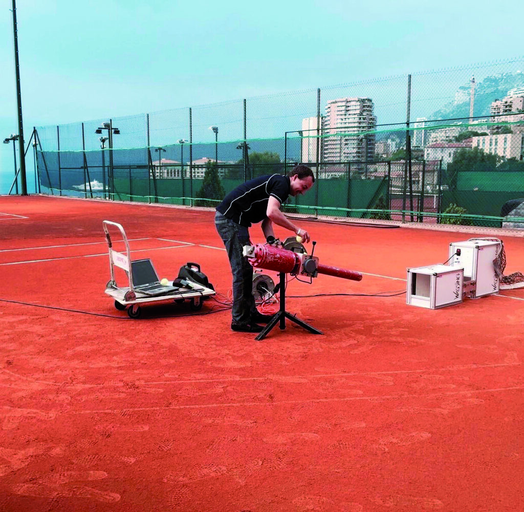 Tecnico RedPlus durante la posa delle linee su campo da tennis indoor in terra rossa