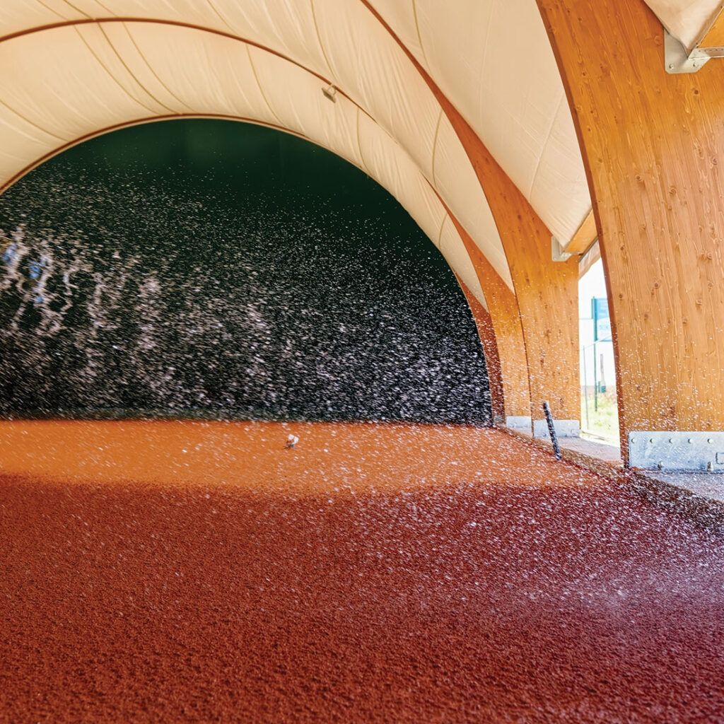 Beregenen bij het onderhoud van een rode gravelbaan van RedPlus in een hal